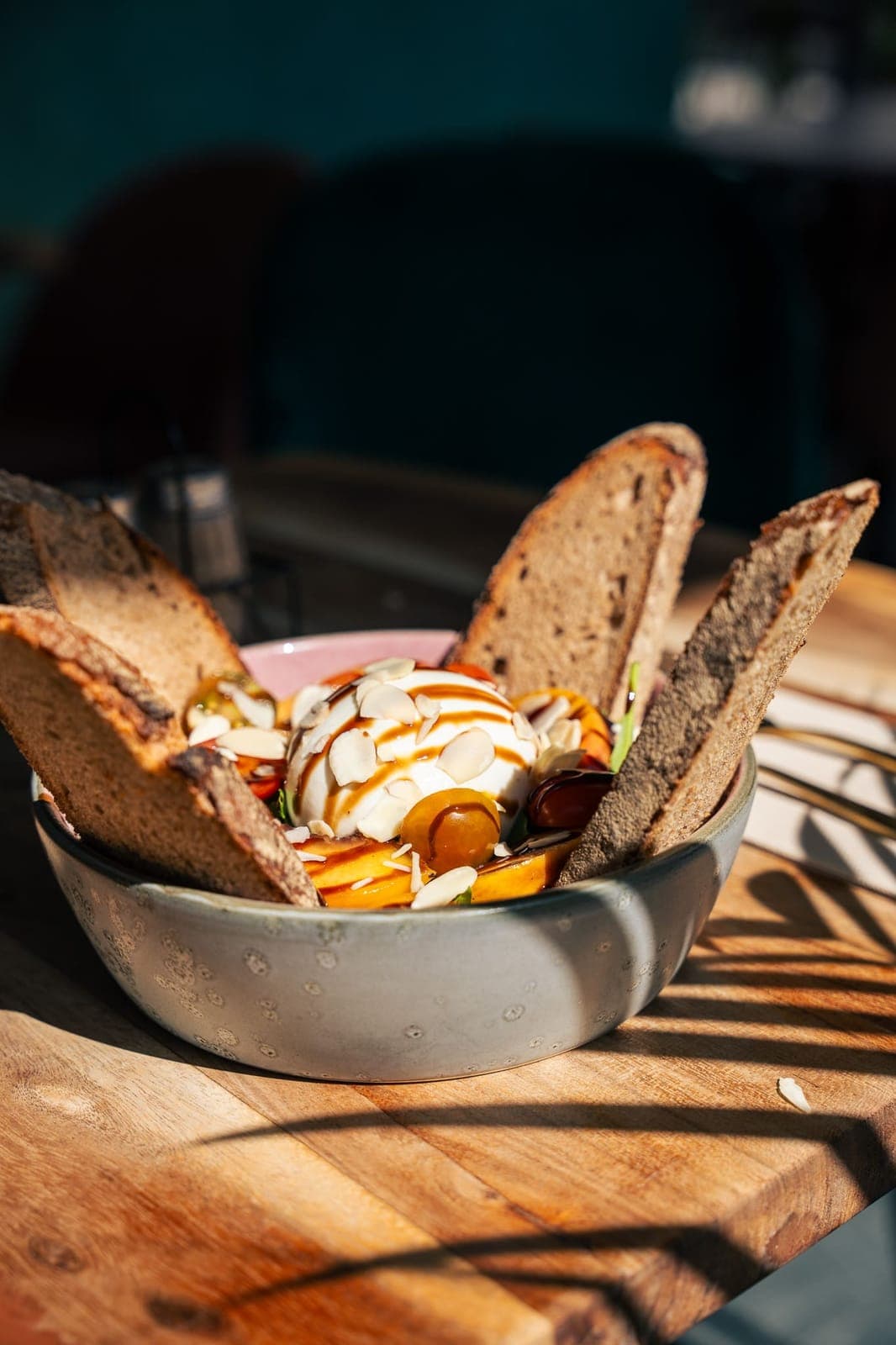 Burrata mit Tomaten, Mandeln und Sauerteigbrot in einer Schale